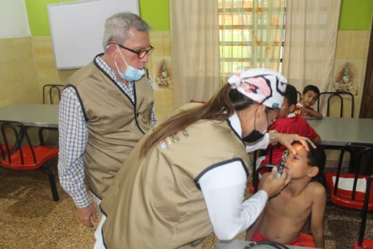 SAI Delivers Free Medical Check-Ups to Venezuelan Orphans SAI (South American Initiative), a dedicated non-profit organization, provides free health check-ups to orphaned children in Venezuela. In this image, a compassionate medical professional conducts an oral examination for a young orphan, ensuring they receive essential care and treatment. Through generous donations and volunteer support, SAI continues its mission to safeguard the health and well-being of vulnerable children by offering free medical services, nutritious food, and educational materials.